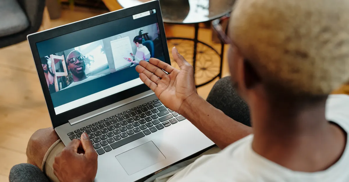 A person on a video call using a laptop in a relaxed home setting.