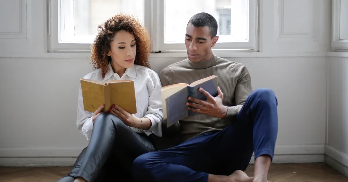 Young couple reading together by a window in a quiet room.