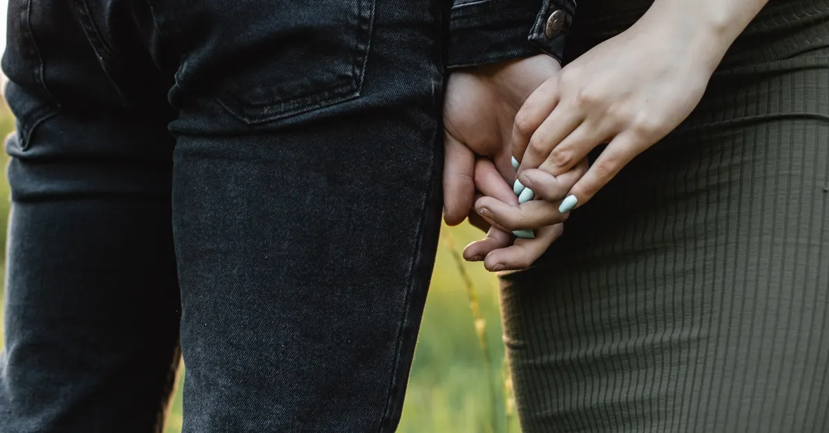 A couple holding hands outdoors, symbolizing connection and intimacy.