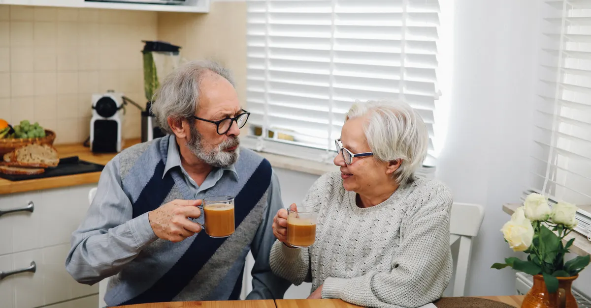 Senior couple enjoying coffee together at home in cozy kitchen setting.