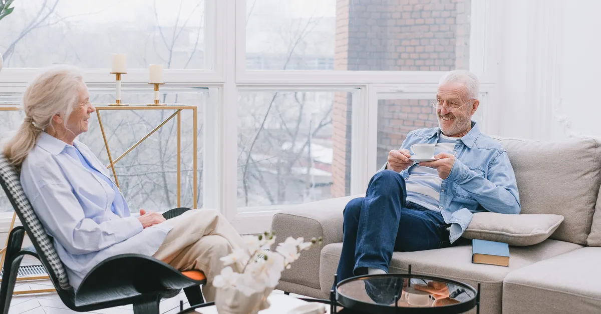 Senior couple relaxing and chatting over tea in a cozy living room.