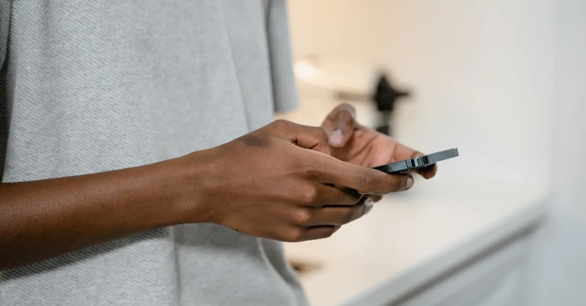Close-up of hands texting on a smartphone indoors, showing the device screen
