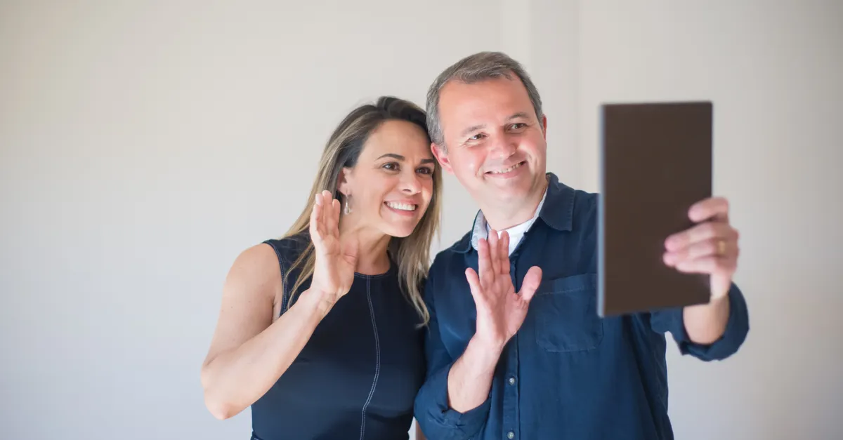 Smiling couple video calling on a tablet indoors.