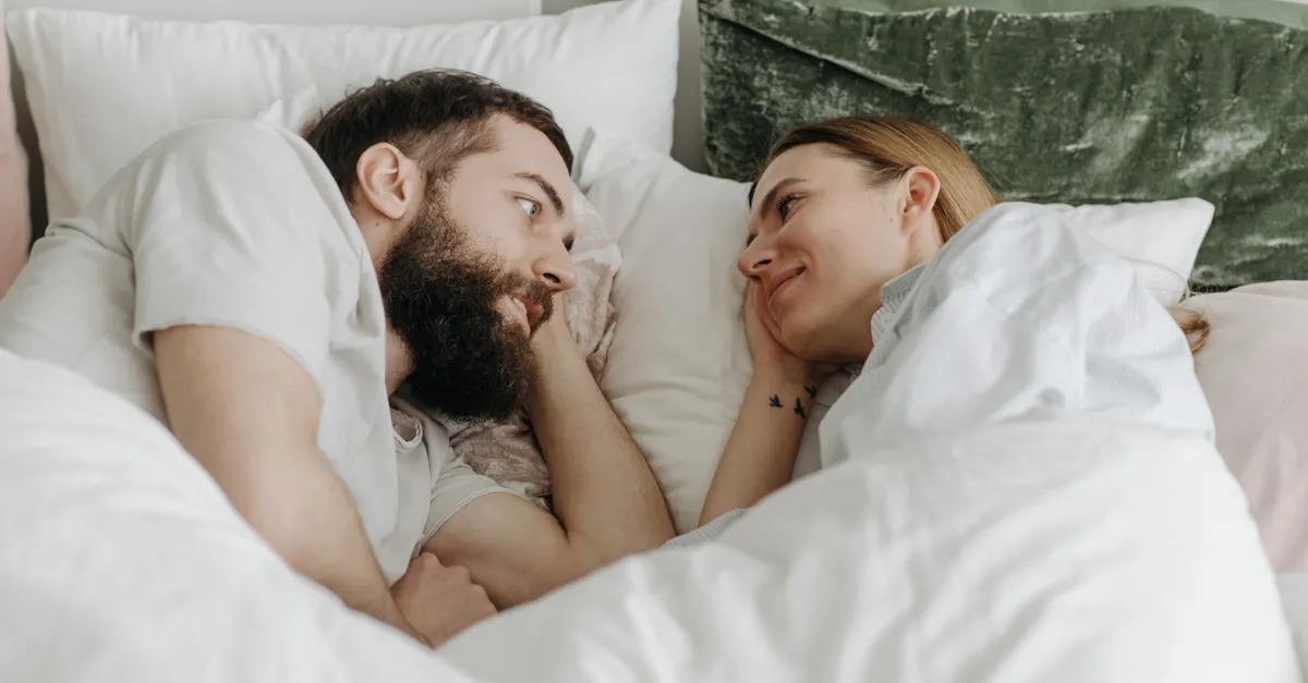 A couple lying in bed sharing a tender moment, conveying love and intimacy.