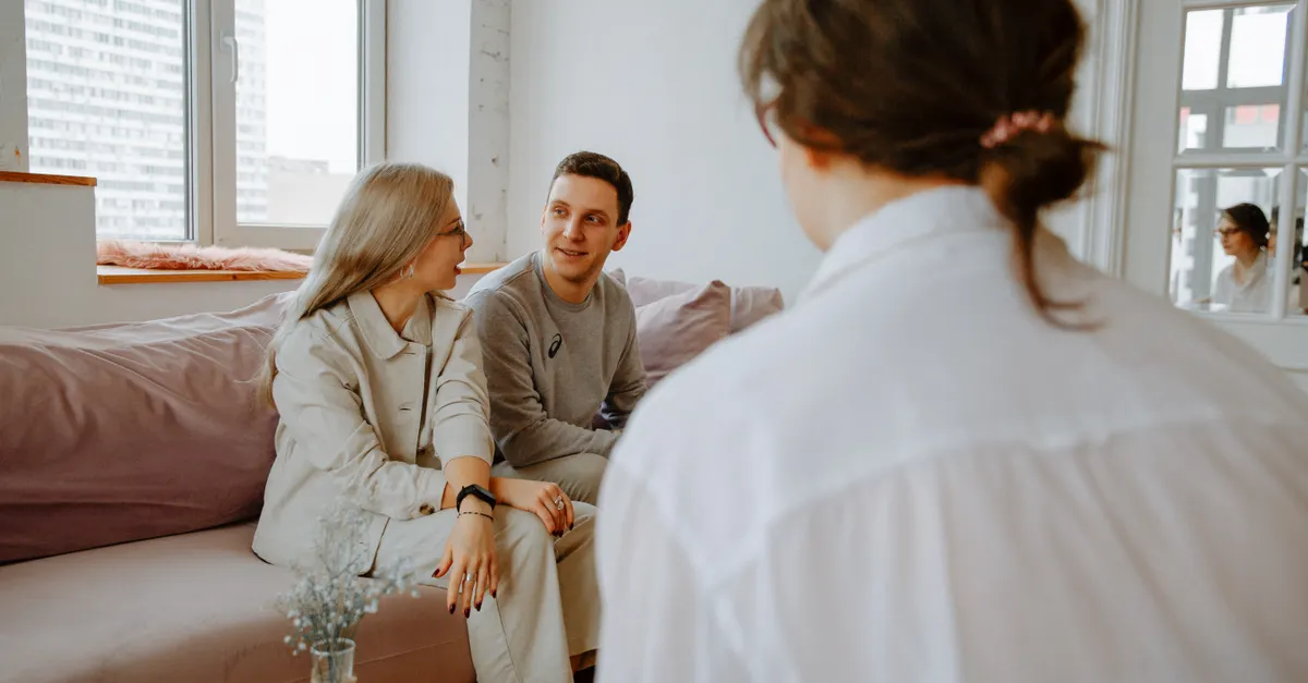 A couple and a therapist sitting in a modern room during a counseling session.
