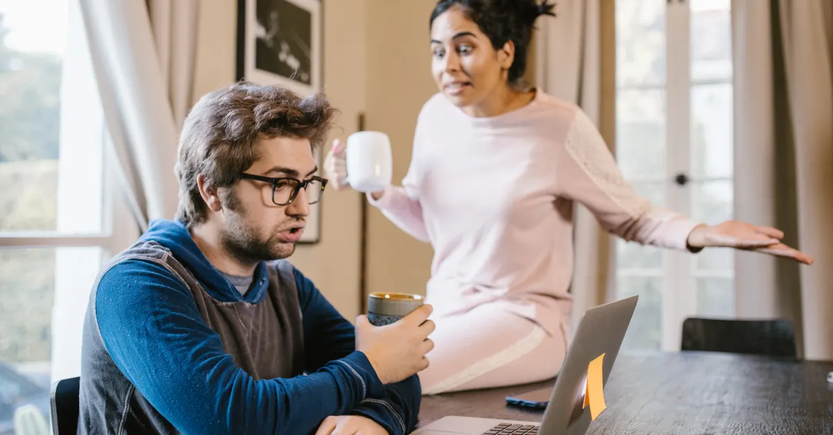 A couple arguing at home with a laptop on the table.
