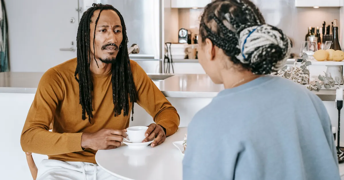 Couple talking over breakfast in a kitchen, facing each other.