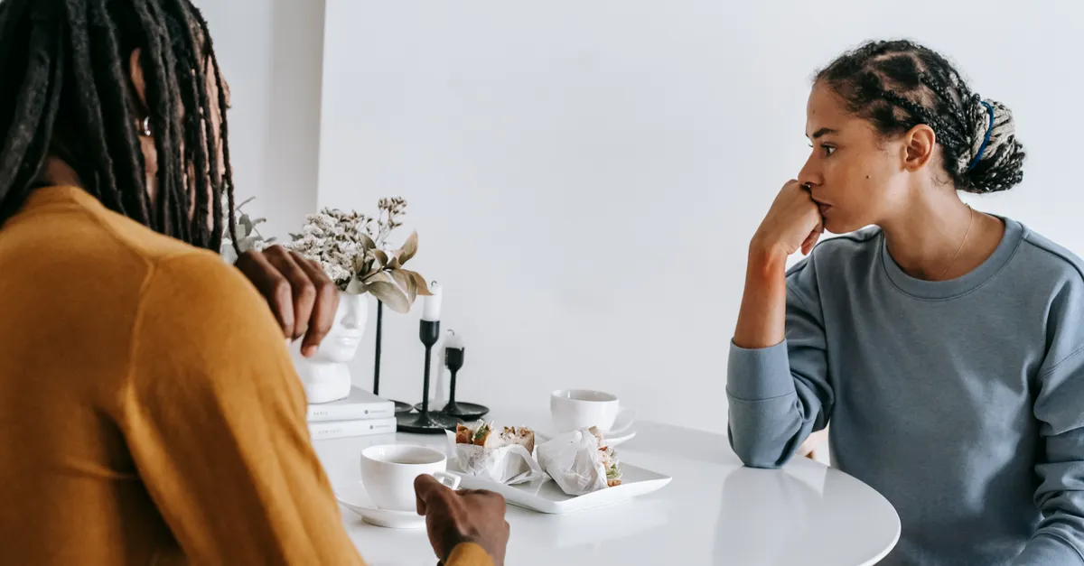 Young man and woman sitting at a table at home having a tense, conflicted conversation