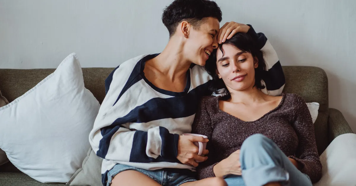 A couple sits on a cozy couch, sharing a tender moment with warmth and affection.