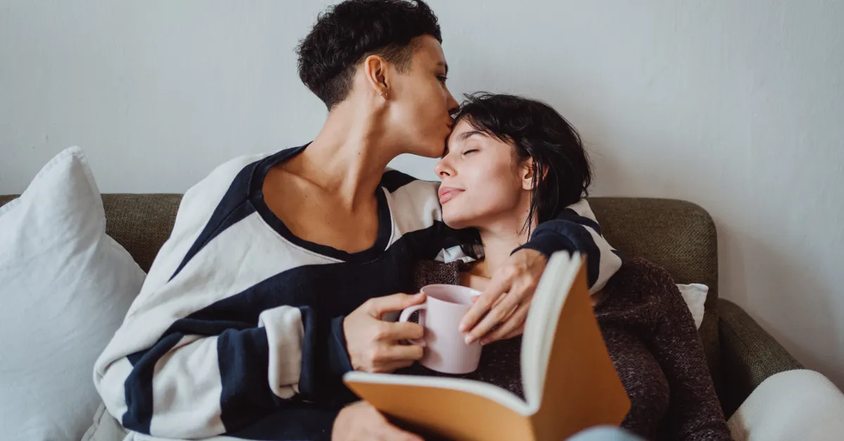 A loving couple enjoys a peaceful moment together, reading and sipping coffee indoors.
